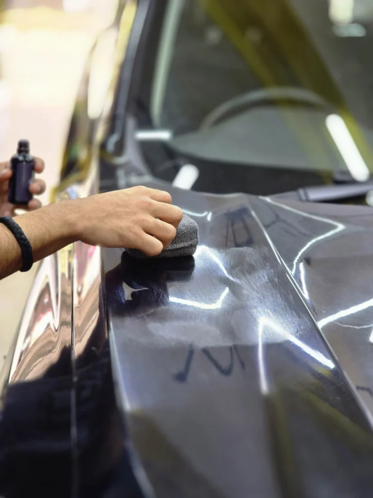 Ceramic coating application on car surface at professional auto detailing service center