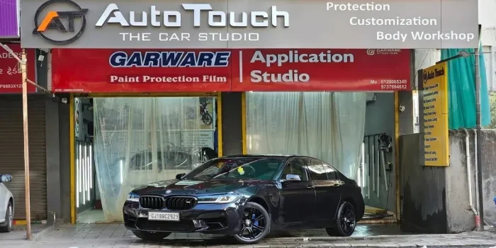 Car technician at a professional automotive detailing and paint protection facility providing expert vehicle care and customization services.